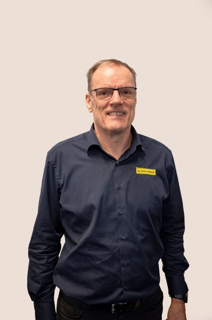 Portræt af Ivan Bastrup Jakobsen, grundlægger af IvanBJ, smilende med briller og navneskilt. Klar til at hjælpe.
