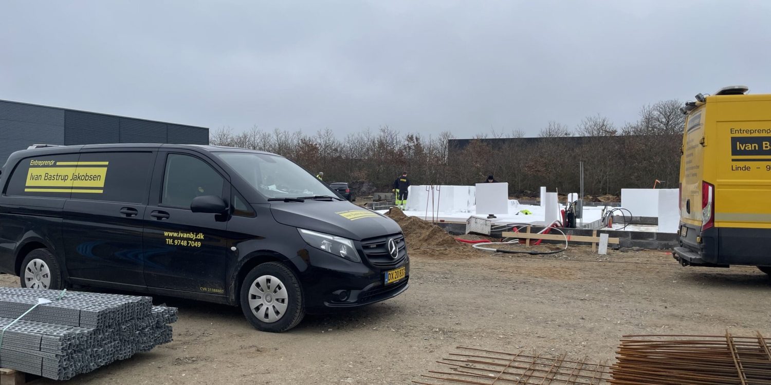 To IvanBJ firmabiler, en sort Mercedes-Benz varebil og en gul Sprinter, på en byggeplads med fundamentisolering og armering.